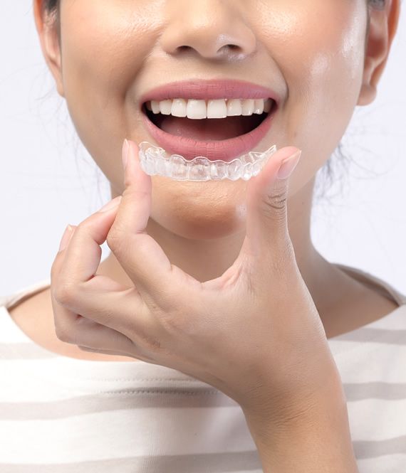 Woman with Invisalign aligner looking in mirror